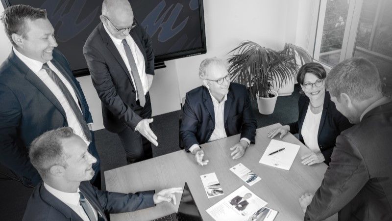 Das Team von WJU in Köln als Gruppenbild an einem Tisch bei einer angeregten Diskussion